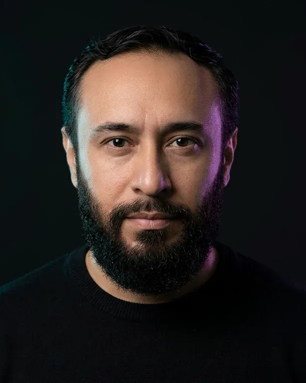 Retrato de Isaac Melz, ingeniero en automatización y desarrollador, sobre fondo oscuro con luz cyan y violeta.
